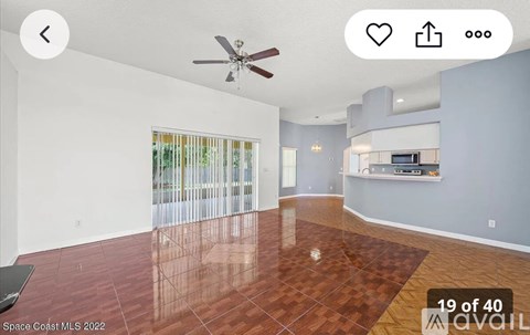 A spacious room with a ceiling fan and a large window with blinds.