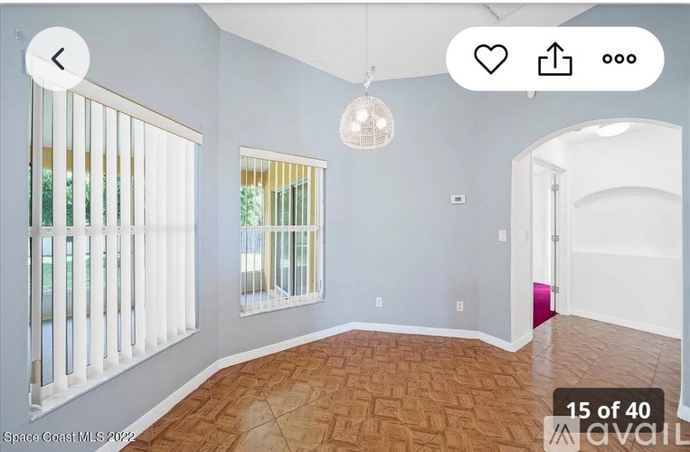 A room with a wooden floor and a window with blinds.