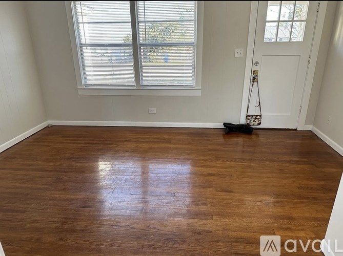 A room with wooden flooring and a window with blinds.