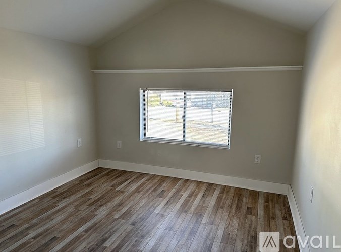 A room with wooden flooring and a window with blinds.