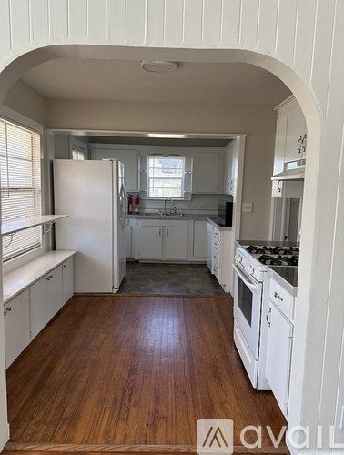 A kitchen with white cabinets and a wooden floor.