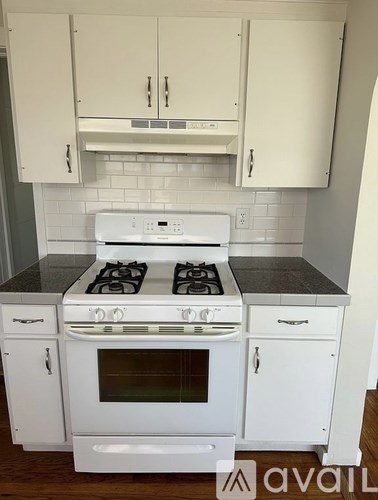 A white stove and oven in a kitchen with white cabinets.