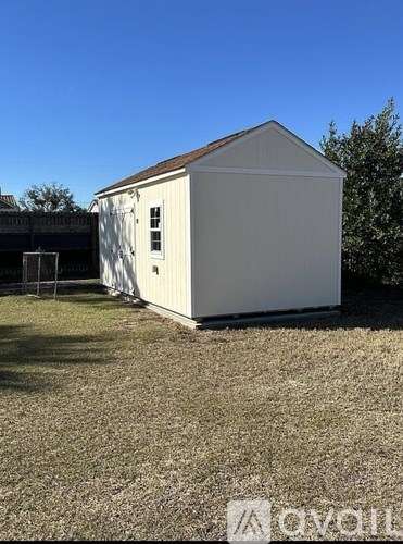 A white shed sits in a grassy field.