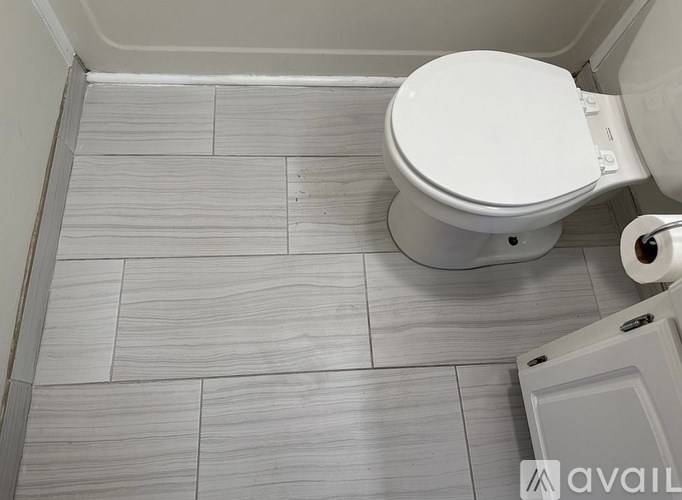 A white toilet in a bathroom with grey tiles.