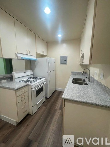 A kitchen with a stove, refrigerator, and sink.