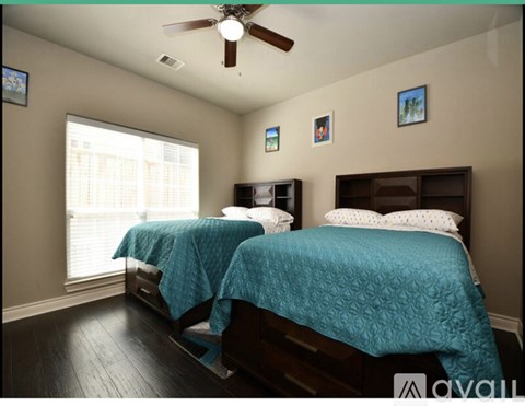A bedroom with two beds and a ceiling fan.