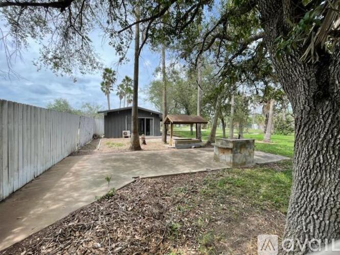 A backyard with a concrete patio, a tree, and a wooden gazebo.