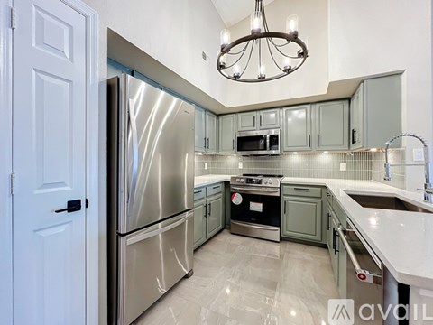 A kitchen with a stainless steel refrigerator and a chandelier hanging from the ceiling.