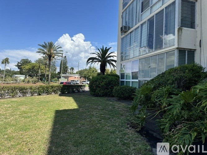 A grassy area with a building and trees in the background.