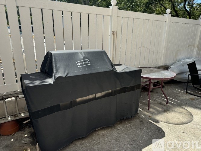 A BBQ grill covered in a black cloth is on a patio.