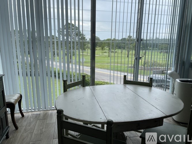 A table and chairs are on a balcony with a view of a field.