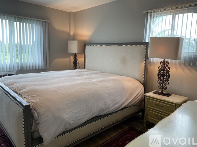 A bedroom with a large bed and two lamps.