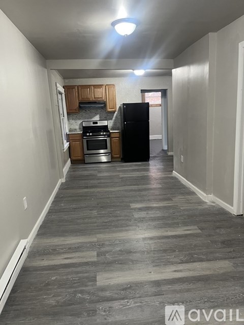A kitchen with wooden cabinets and a black refrigerator.