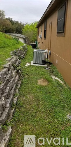 A grassy area with a stone wall and a brown building in the background.