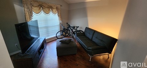 A living room with a black leather couch and a television.