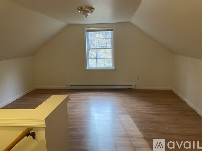 A room with a window and wooden flooring.