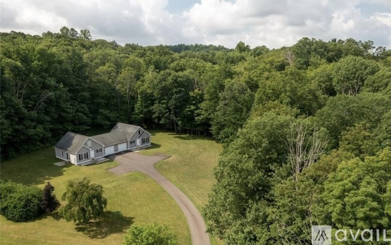A house is surrounded by trees in a grassy area.