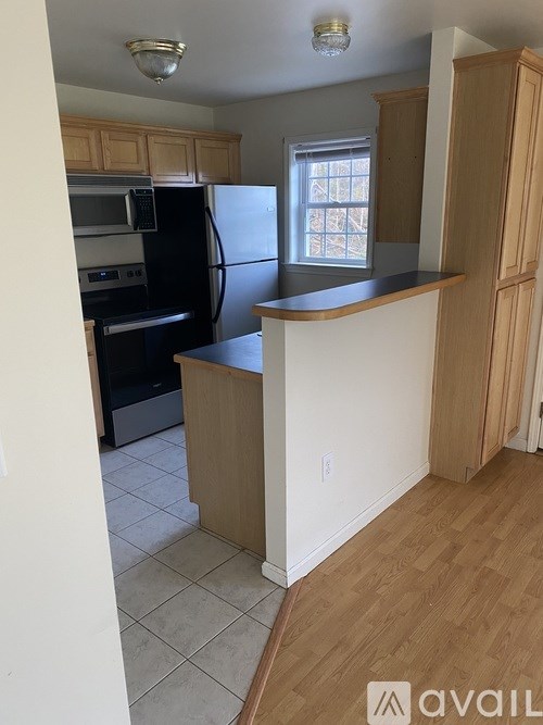 A kitchen with wooden cabinets and a black fridge.