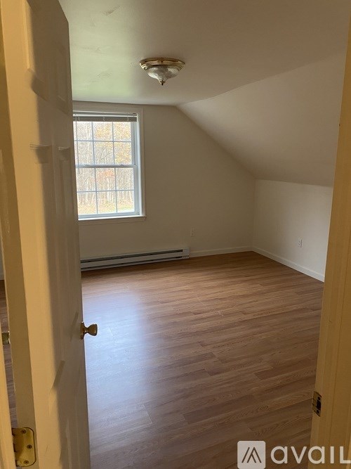 A room with a window and wooden flooring.
