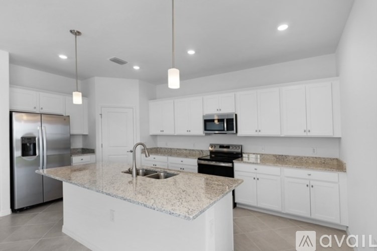 A modern kitchen with a granite countertop and stainless steel appliances.