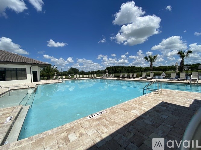 A large outdoor swimming pool with a tiled edge and a building in the background.