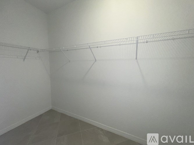 Empty room with a white wall and a wire shelf.