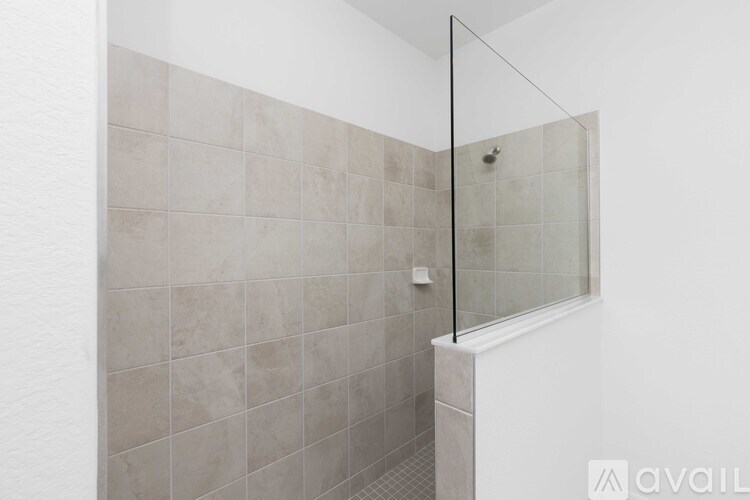 A tiled shower with a glass door is shown.