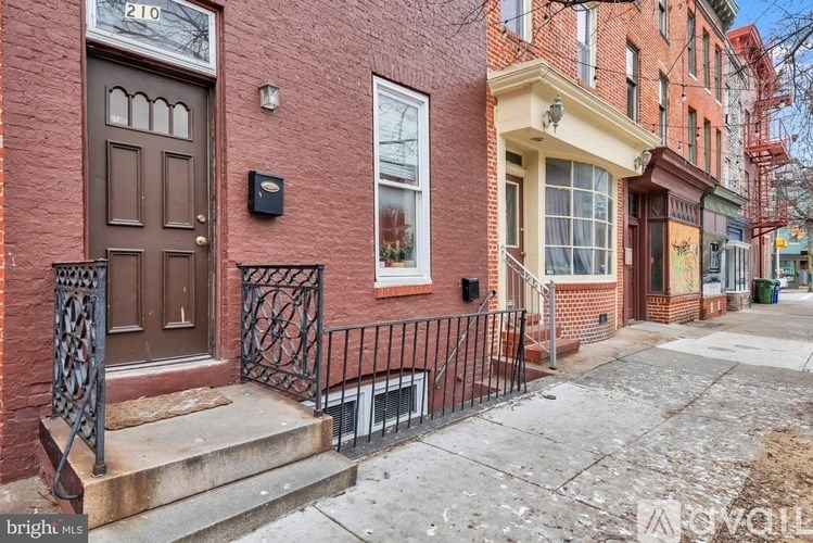 A red brick house with a brown door and a black metal fence.