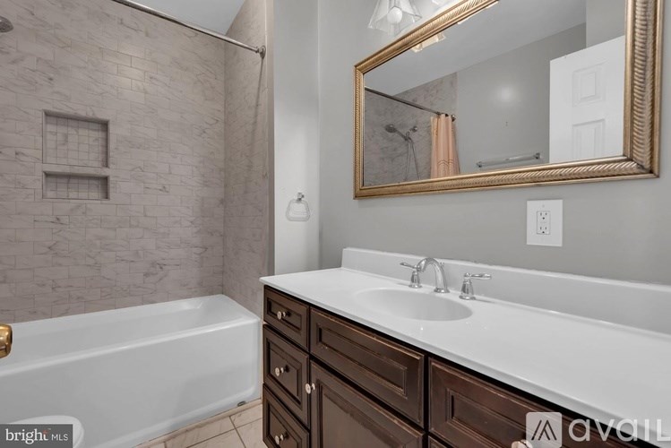 A bathroom with a white tub, sink, and a mirror.