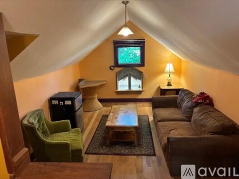 A living room with a green chair, a brown couch, and a television mounted on the wall.