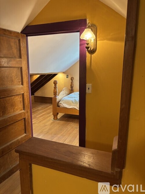 A bedroom with a bed and a wooden staircase.