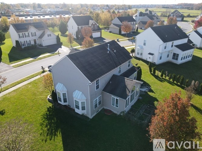 A bird's eye view of a white house with a black roof in a residential area.