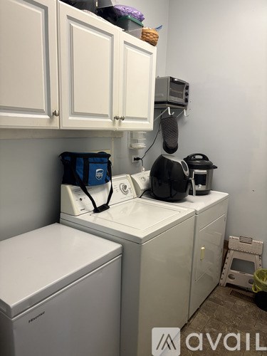 A room with a grey floor and a grey wall with a white shelf on the left side.