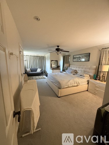 A bedroom with a large bed and a ceiling fan.