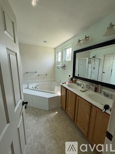 A bathroom with a tub, sink, and mirror.