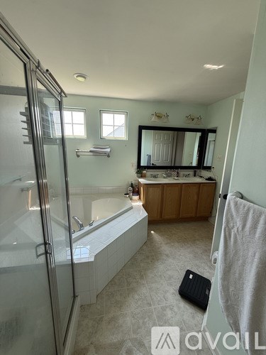 A bathroom with a glass shower stall and a bathtub.
