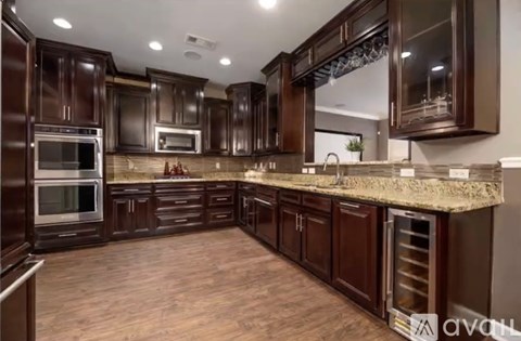 A kitchen with dark brown cabinets and a granite countertop.