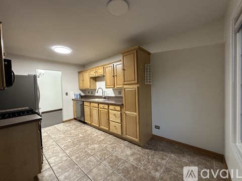 A kitchen with wooden cabinets and a tiled floor.