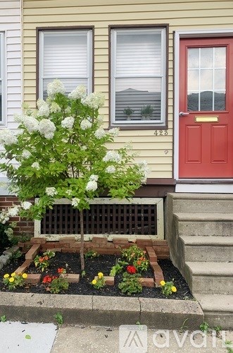 A house with a red door and a flower bed in front.