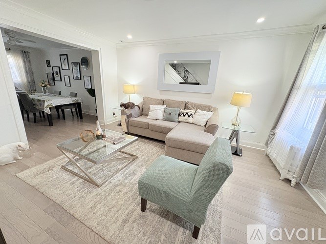 A living room with a grey sofa, a glass coffee table, and a green armchair.
