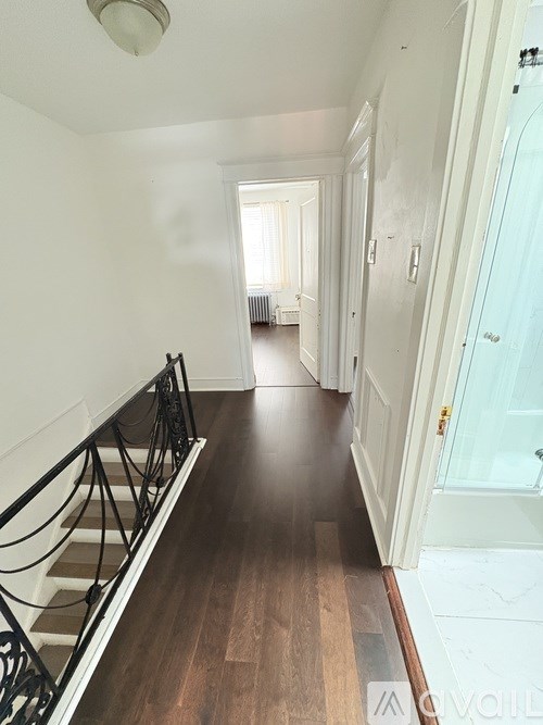 A hallway with a staircase on the left and a door on the right.