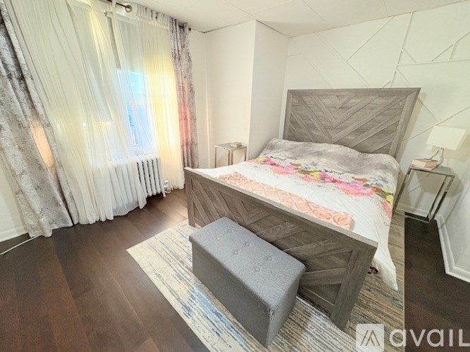 A bedroom with a large bed and a window with curtains.