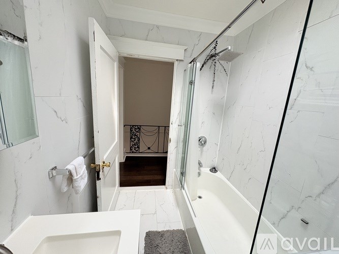 A bathroom with a marble wall and a glass shower stall.