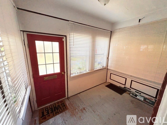 A room with a red door and a window with blinds.