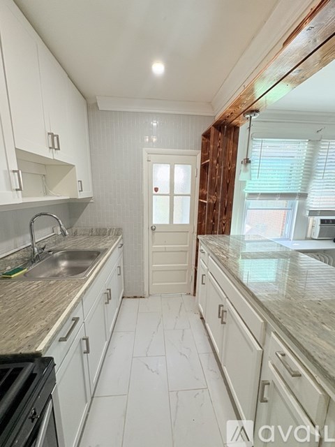 A kitchen with white cabinets and a marble countertop.