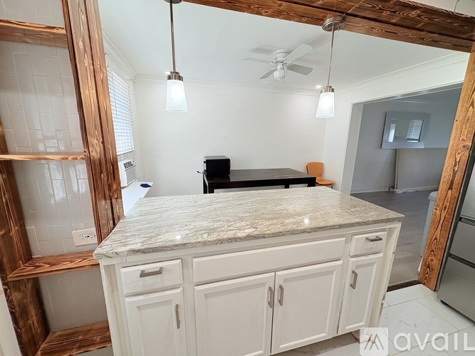 A kitchen with a marble countertop and white cabinets.