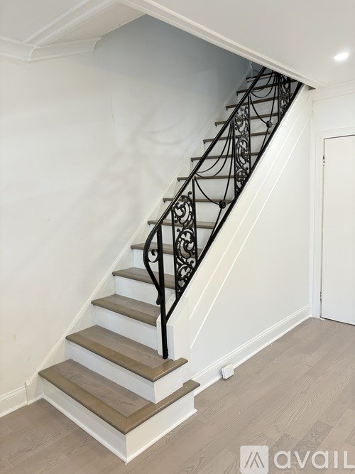 A staircase with a black metal railing and wooden steps.