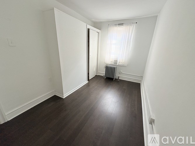A room with a wooden floor and a window with blinds.