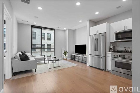 A modern kitchen with stainless steel appliances and a living area with a couch and a coffee table.