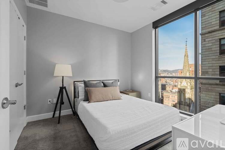A bedroom with a large bed and a view of a cityscape through a window.